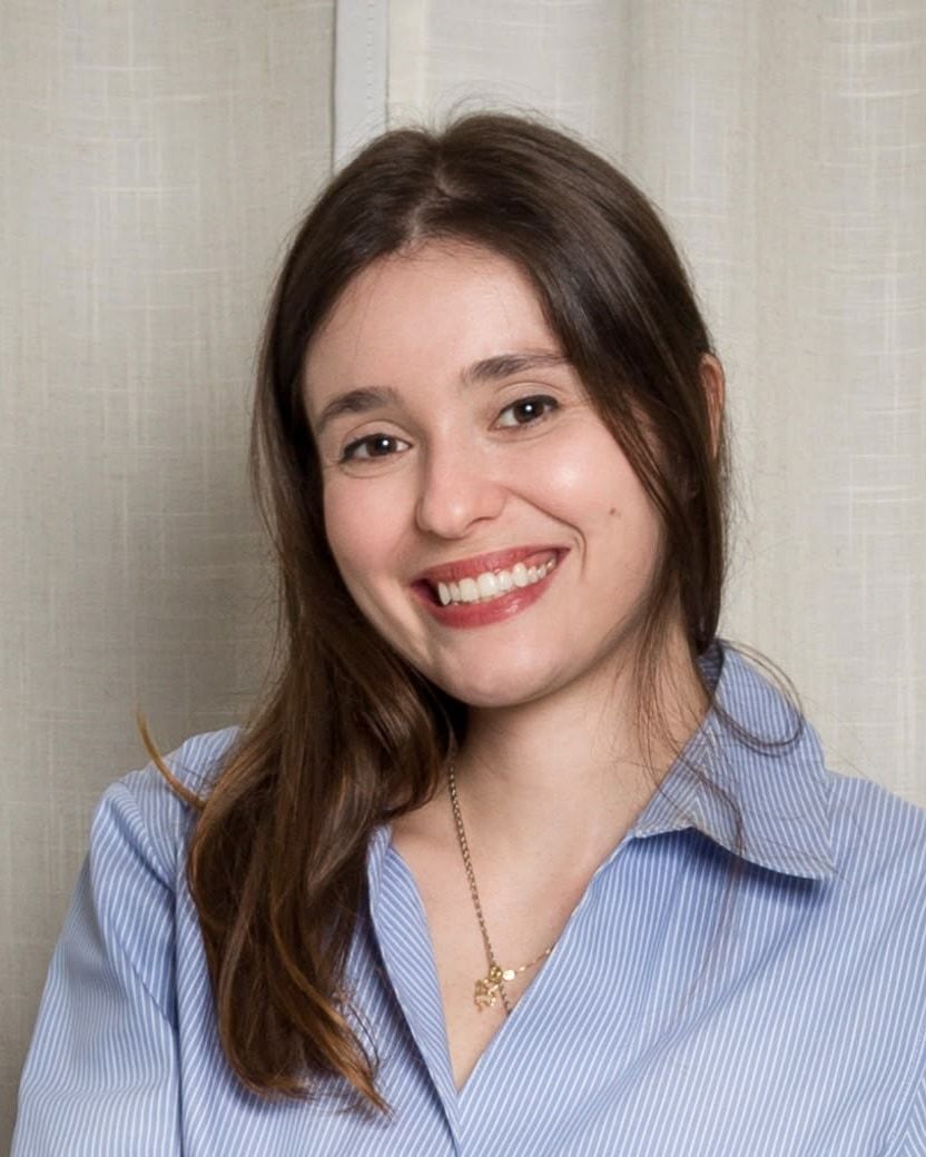 Mariana Muliterno Gomes sorrindo, de camisa azul listrada